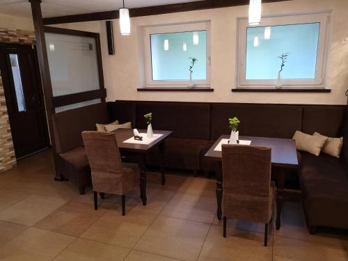 a dining room with two tables and chairs and windows at Pas Nerijų in Skuodas