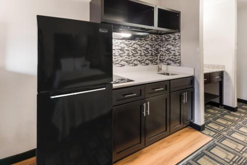 a kitchen with a black refrigerator and a sink at Suburban Studios Mason Hwy 42 in Mason