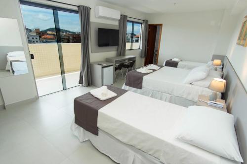 a hotel room with two beds and a television at Hotel Mirante do Forte in Cabo Frio