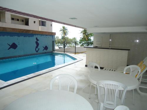 a swimming pool with white tables and chairs next to a white table and chairsktop at Flat em Boa Viagem in Recife