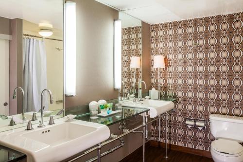 uma casa de banho com 2 lavatórios, um WC e um espelho. em Hotel Derek Houston Galleria em Houston