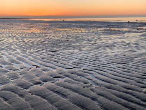 a beach with ripples in the sand at sunset at "ZeeLandZon" Holiday home by the lake with Jacuzzi and Sauna in Herkingen