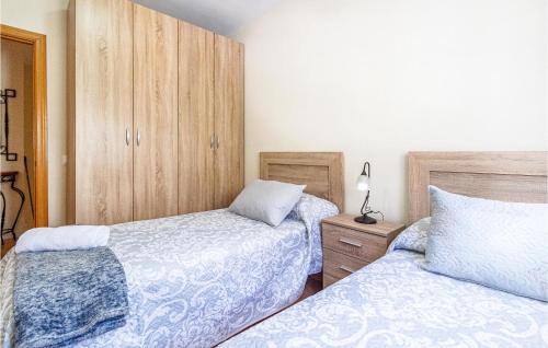 a bedroom with two beds and a wooden cabinet at Awesome Home In Benaoján in Benaoján