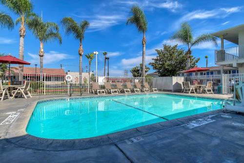 a swimming pool with palm trees in a resort at Motel 6-Stanton, CA- Anaheim West in Stanton