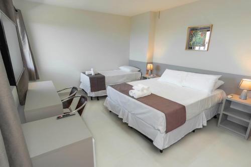 a hotel room with two beds and a chair at Hotel Mirante do Forte in Cabo Frio