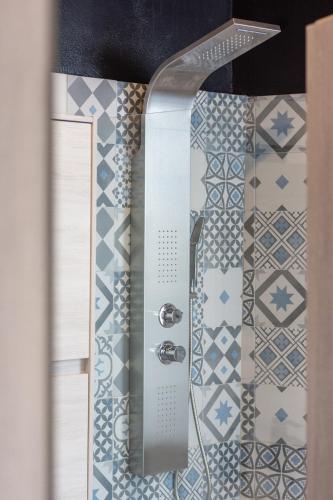 a shower in a bathroom with blue and white tiles at Milos Guesthouse in Triovasálos