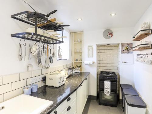a kitchen with white cabinets and a black stove at Dolwar in Amlwch
