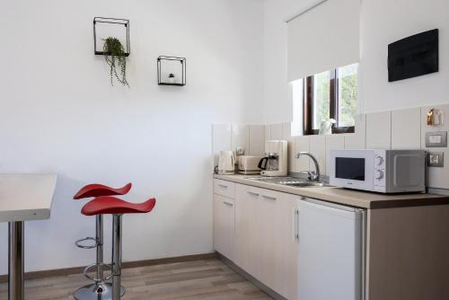 a kitchen with white cabinets and a red stool at Terinikos Sunny Garden Hotel & Junior Suites New Renovation 2025 in Ialyssos