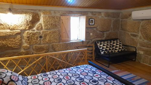 Cette chambre est dotée d'un mur en pierre, d'un lit et d'une fenêtre. dans l'établissement Lagar da Silveira, à Penafiel