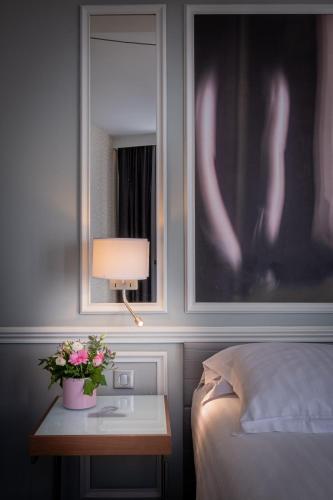 a bedroom with a bed and a table with flowers on it at Hotel Litteraire Le Swann, BW Premier Collection in Paris
