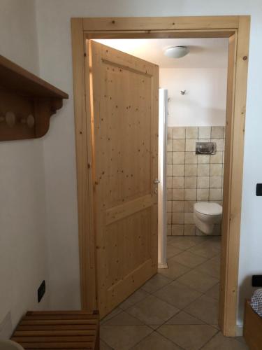La salle de bains est pourvue de toilettes et d'une porte en bois. dans l'établissement Maso Arlanch 8, à Vallarsa