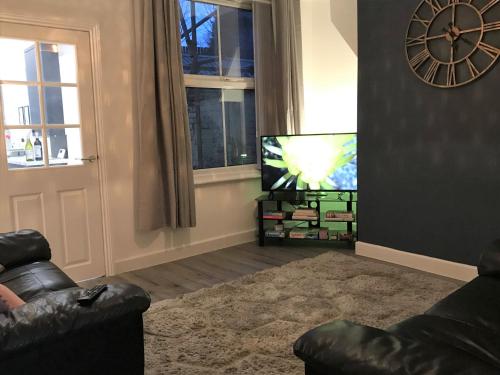 salon z kanapą, telewizorem i oknem w obiekcie Stylish modern 3-bed house nr Manchester city ctr w mieście Whitefield