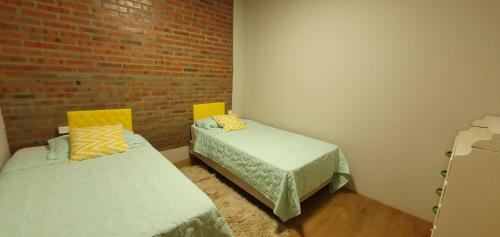 a room with two beds and a brick wall at Ivy House Apart Hotel in Ciudad del Este
