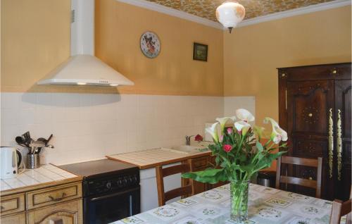 une cuisine avec une table avec un vase de fleurs dessus dans l'établissement Holiday Home Saint Jean-Trolimon - 02, à Saint-Jean-Trolimon