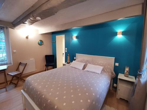 une chambre avec un grand lit avec un mur bleu dans l'établissement Le rez de jardin, à Honfleur