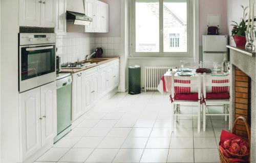 une cuisine avec des armoires blanches et une table à l'intérieur dans l'établissement Beach Front Apartment, à Saint-Benoît-des-Ondes