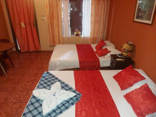 two beds in a hotel room with red at Hotel Torre Fuerte in Venecia