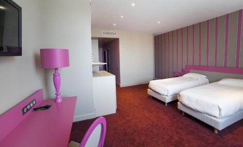 a hotel room with two beds and a pink lamp at The Originals Boutique, La Maison Rouge, Lens Ouest in Noeux-les-Mines
