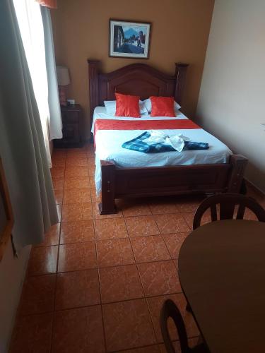 a bedroom with two beds with red pillows and a table at Hotel Torre Fuerte in Venecia