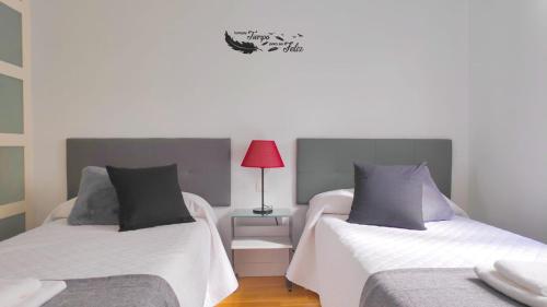 a bedroom with two beds and a red lamp on a table at APARTAMENTO LA REAL in Nájera