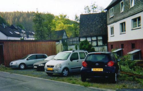 three cars parked in a parking lot next to a house at Pension Deimel in Hallenberg
