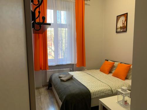 een slaapkamer met een bed en een raam met oranje gordijnen bij Discover Cracow APARThostel in Krakau