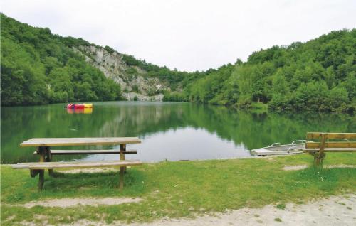two picnic tables and a boat on a lake at Holiday Home In Montsernelle in Lithaire