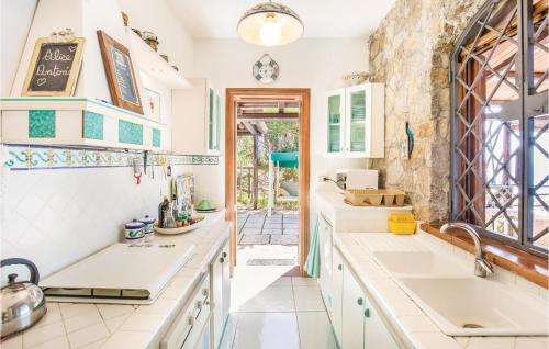 uma cozinha com balcões brancos e uma parede de pedra em La Canora em Parghelia