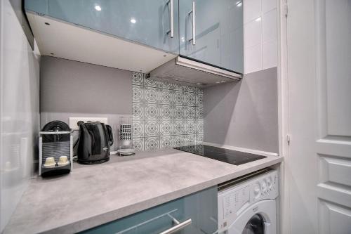 Il comprend une petite cuisine équipée d'une cuisinière. - un four supérieur à côté d'un lave-linge dans l'établissement IMMOGROOM - Cosy Studio - Forville market - AC, à Cannes