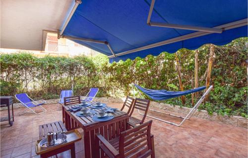 eine Terrasse mit einem Tisch, Stühlen und einem blauen Sonnenschirm in der Unterkunft Stunning Apartment In Marina Di Ragusa in Marina di Ragusa