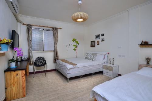 1 dormitorio con 2 camas, mesa y silla en Ding Ding Homestay, en Jinhu