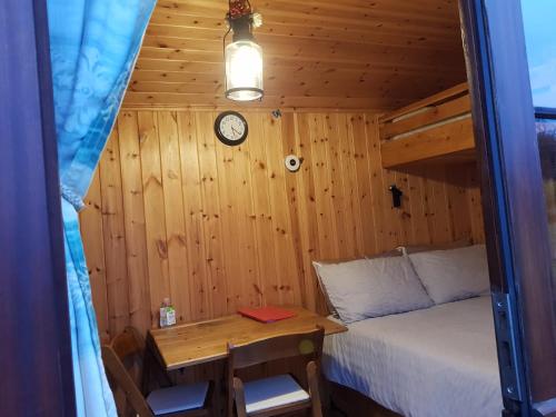 a bedroom with a bed and a table and a clock at Cozy Cabine Retreat in Clun in Craven Arms