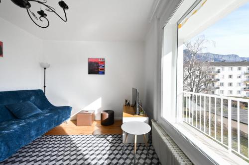 un salon avec un canapé bleu et une grande fenêtre dans l'établissement Le Boileau - Apartment for 4 people parking and balcony CLOSE to the Lake, à Annecy