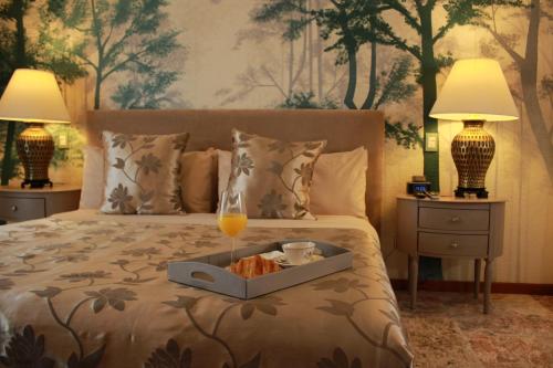 Una cama con una bandeja de comida y una copa de champán. en Santo Refugio Heritage Hotel en Cholula