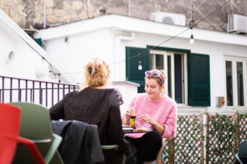 two women sitting at a table in front of a house at Tric Trac Hostel in Naples