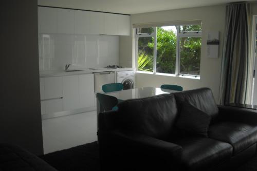 a living room with a couch and a table and a kitchen at Central Park Studio in New Plymouth