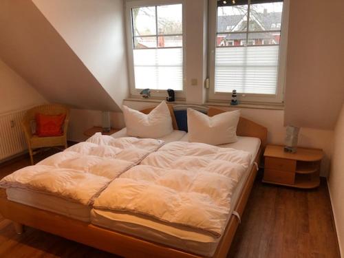 ein großes Bett in einem Zimmer mit zwei Fenstern in der Unterkunft Birkenstr.6 Haus 1 Bodden Pirat in Zingst