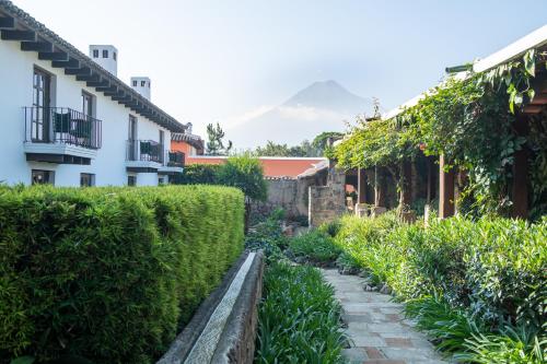 a garden in front of a house with a mountain in the background at Hotel Museo Spa Casa Santo Domingo in Antigua Guatemala