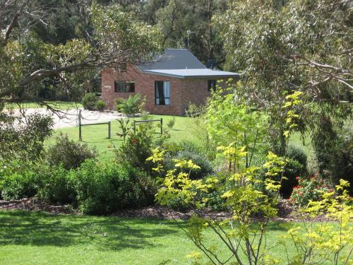 a brick house in the middle of a garden at Prom Coast Holiday Lodge in Waratah Bay