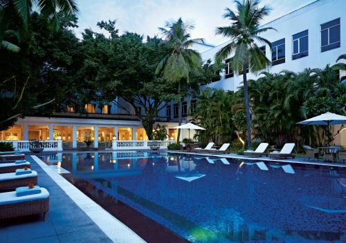 uma piscina de hotel com cadeiras e um edifício em Taj Connemara, Chennai em Chennai