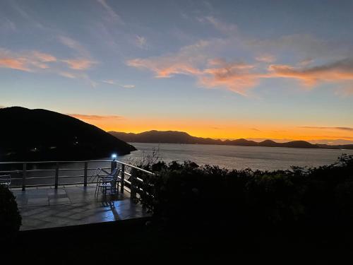 a sunset over the water with a table and chairs at Ocean View Villas in Jost Van Dyke
