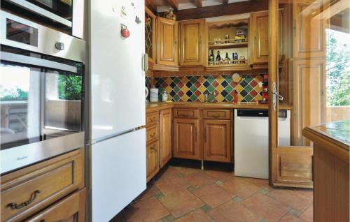 a kitchen with wooden cabinets and a white refrigerator at Beautiful Home In St Paul En Foret in Saint-Paul-en-Forêt