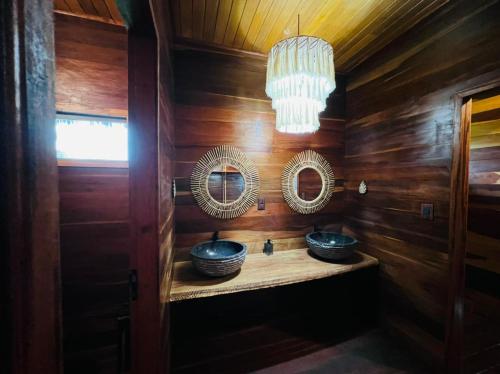a bathroom with two sinks and mirrors and a chandelier at Chalé Rubi in Tutóia