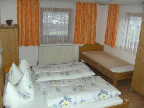 2 Betten in einem Zimmer mit orangefarbenen Vorhängen und Fenstern in der Unterkunft Ferienwohnung Hippach - Monika Sporer in Hippach