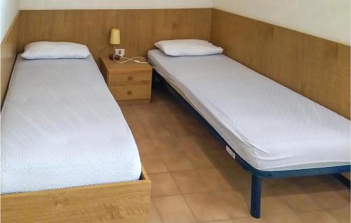 two twin beds in a room with a night stand at Beautiful Apartment In Bibione With Outdoor Swimming Pool in Bibione