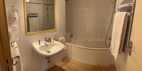a white bathroom with a sink and a shower at Logis Auberge du Fel in Le Fel