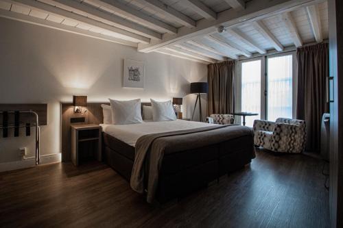 a hotel room with a bed and a large window at Grand Hotel en Résidence De Draak in Bergen op Zoom