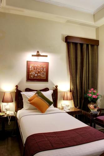 a bedroom with a bed and two tables and two lamps at Palace On Ganges - Heritage Hotel in Varanasi