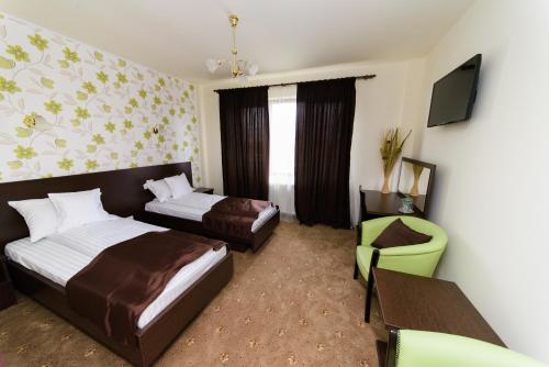 a hotel room with two beds and a chair at Hotel Miky in Arad