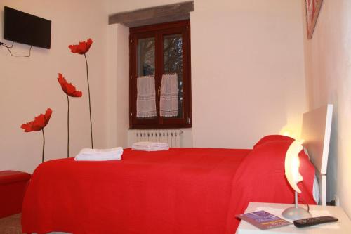 a bedroom with a red bed with red sheets and flowers at La Loggetta in Bagnoregio